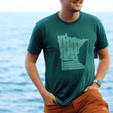 Load image into Gallery viewer, Male wearing green t-shirt has minnesota cut-out and trees, tent, canoe on inside