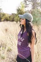 Load image into Gallery viewer, Woman wearing a purple 'I'd Hike That' shirt and cap in a natural setting