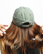 Load image into Gallery viewer, Person wearing a green baseball cap with wavy hair on a white background