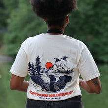 Load image into Gallery viewer, model wearing loon tshirt. Back of shirt showing Loon spreading it's wings in front of mountain scenery