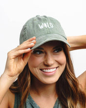 Load image into Gallery viewer, Woman wearing a green cap with 'WILD' text on a white background