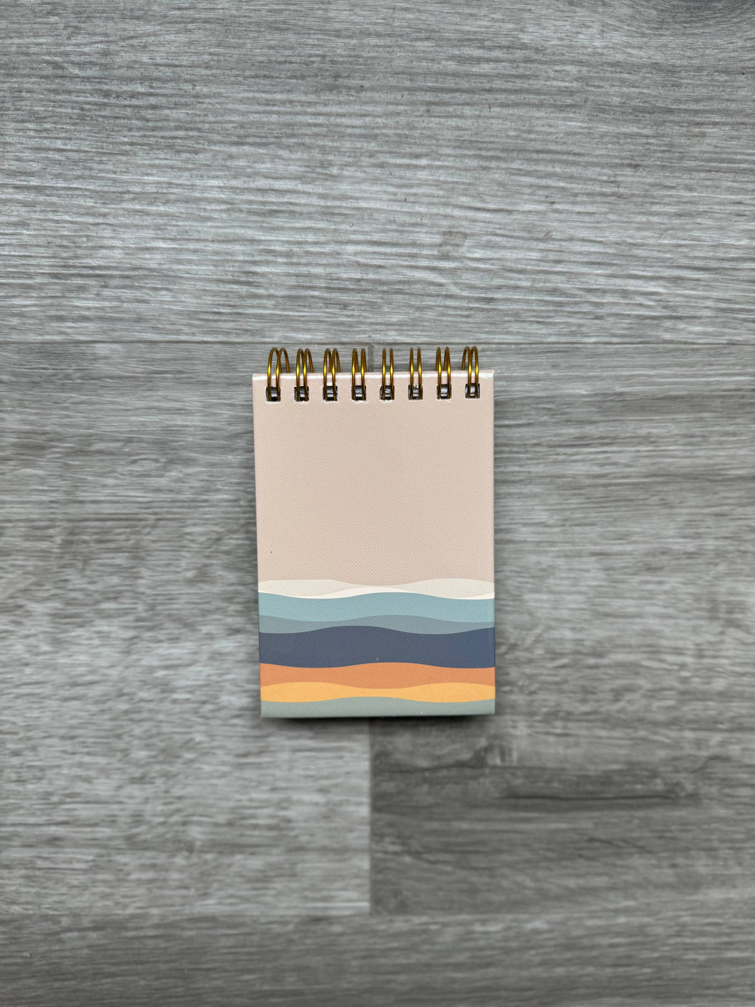 Small spiral notepad with tan cover and wave rolling hills design