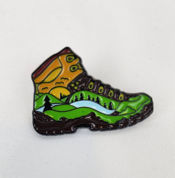 Hiking boot pin with forest, river, and sun