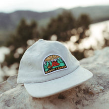 Load image into Gallery viewer, white hat sitting on a rock with happy camper patch on it
