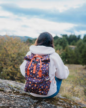 Load image into Gallery viewer, Woman sitting on rock looking at scenery with wildflower backpack on
