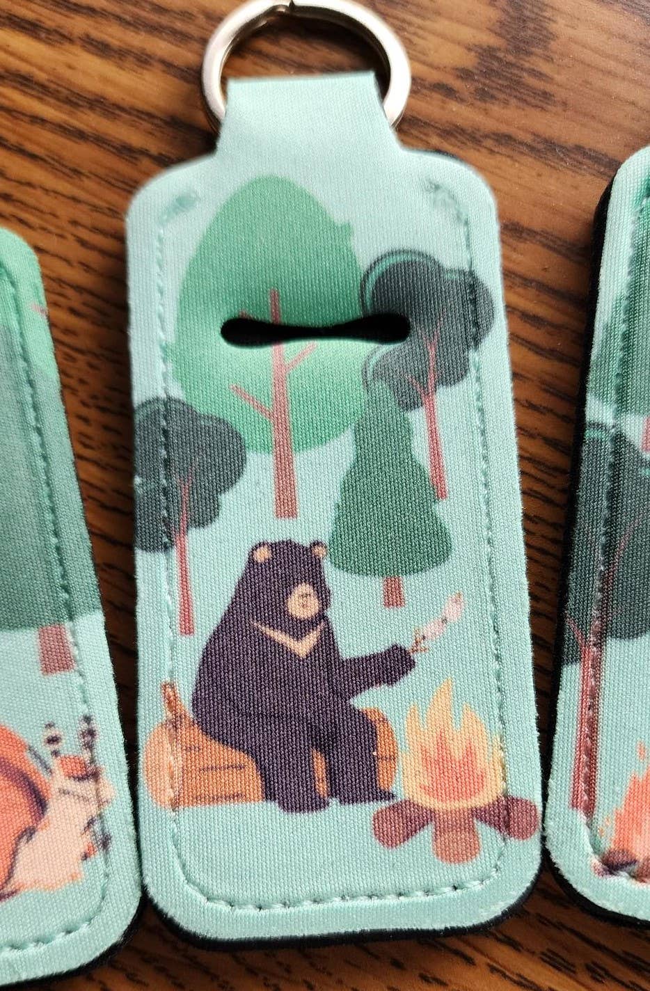 Neopreme chapstick holder keychain with bear roasting marshmallows by a campfire