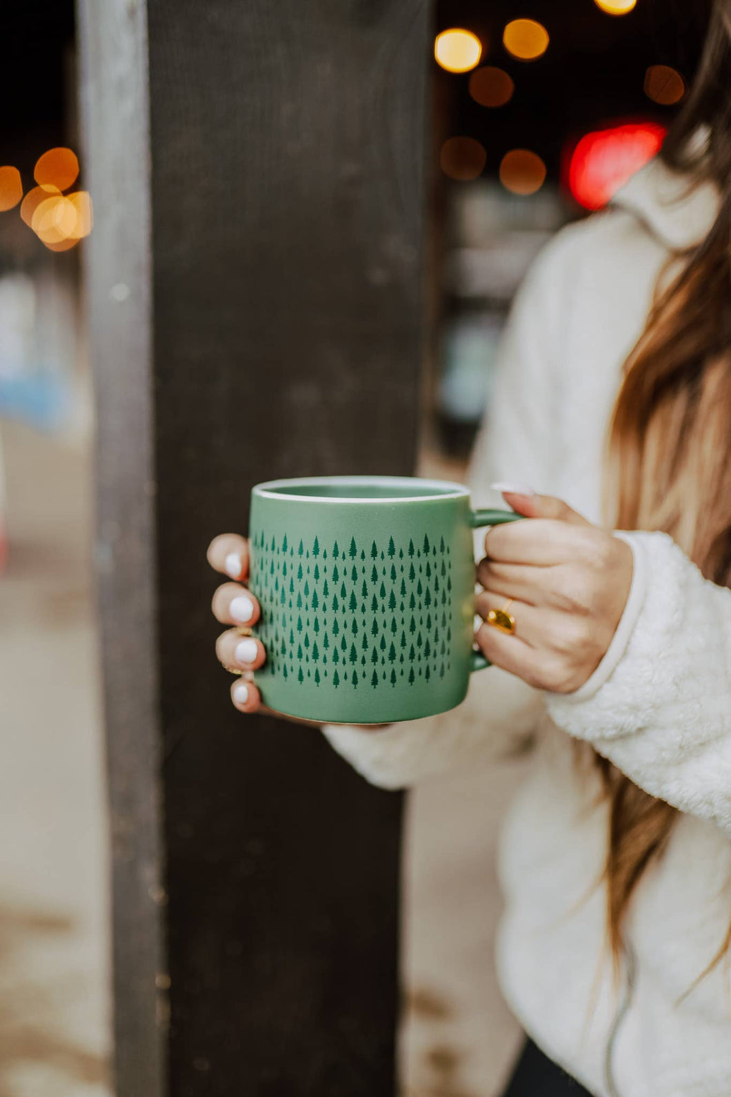 woman holding green mug with small trees printed all around it