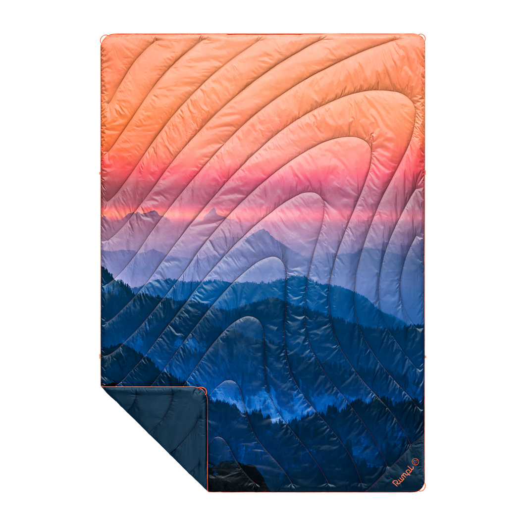 Outdoor puffy blanket with mountain sunset scene of blue, pink, and orange.