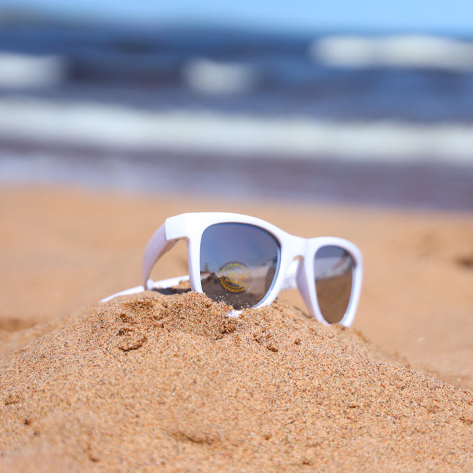 White youth sunglasses in the sand at the beach