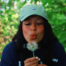 Load image into Gallery viewer, Green hat with a blue loon being worn by girl blowing a dandelion 
