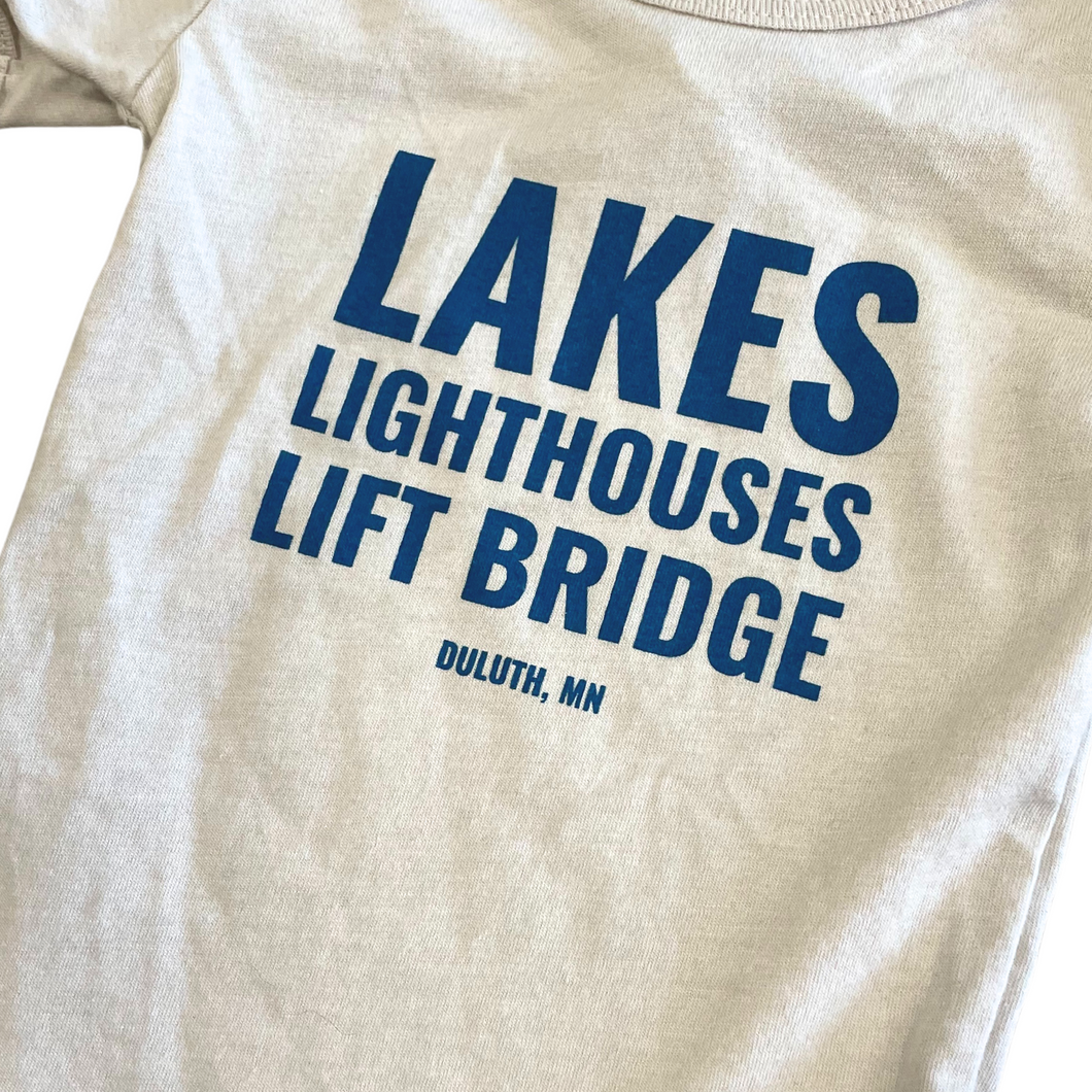 Cream onesie with blue writing that says Lakes Lighthouses Lift Bridge Duluth, MN