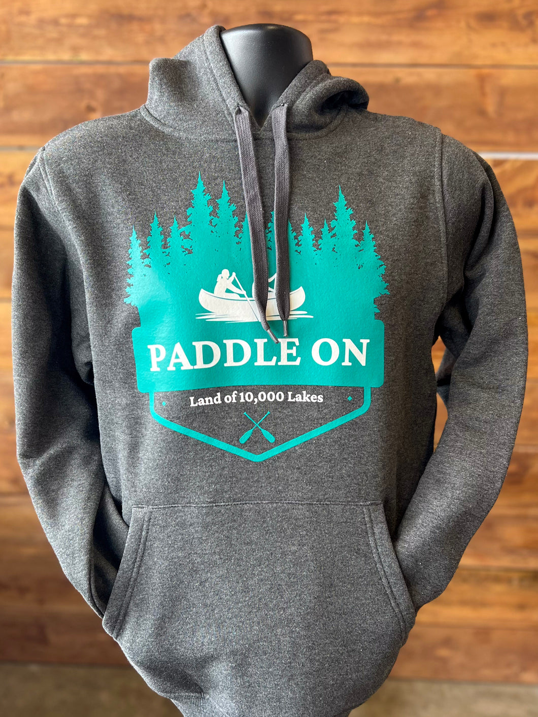 Grey hooded sweatshirt that says Paddle On land of 10,000 lakes