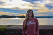 Load image into Gallery viewer, Mauve crewneck that says Lake Superior. Model in front of sunset at beach
