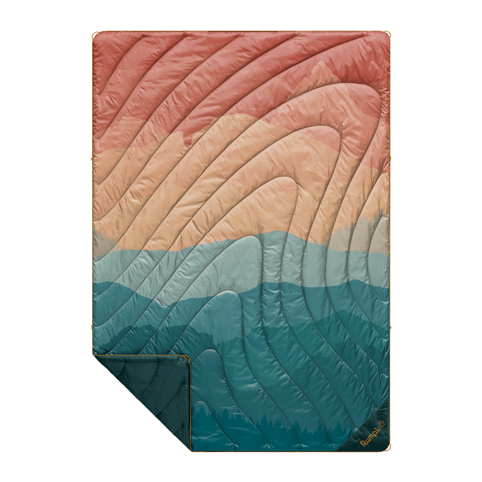 Puffy blanket that shows sunset fade design with peach, orange, teal, and dark blue