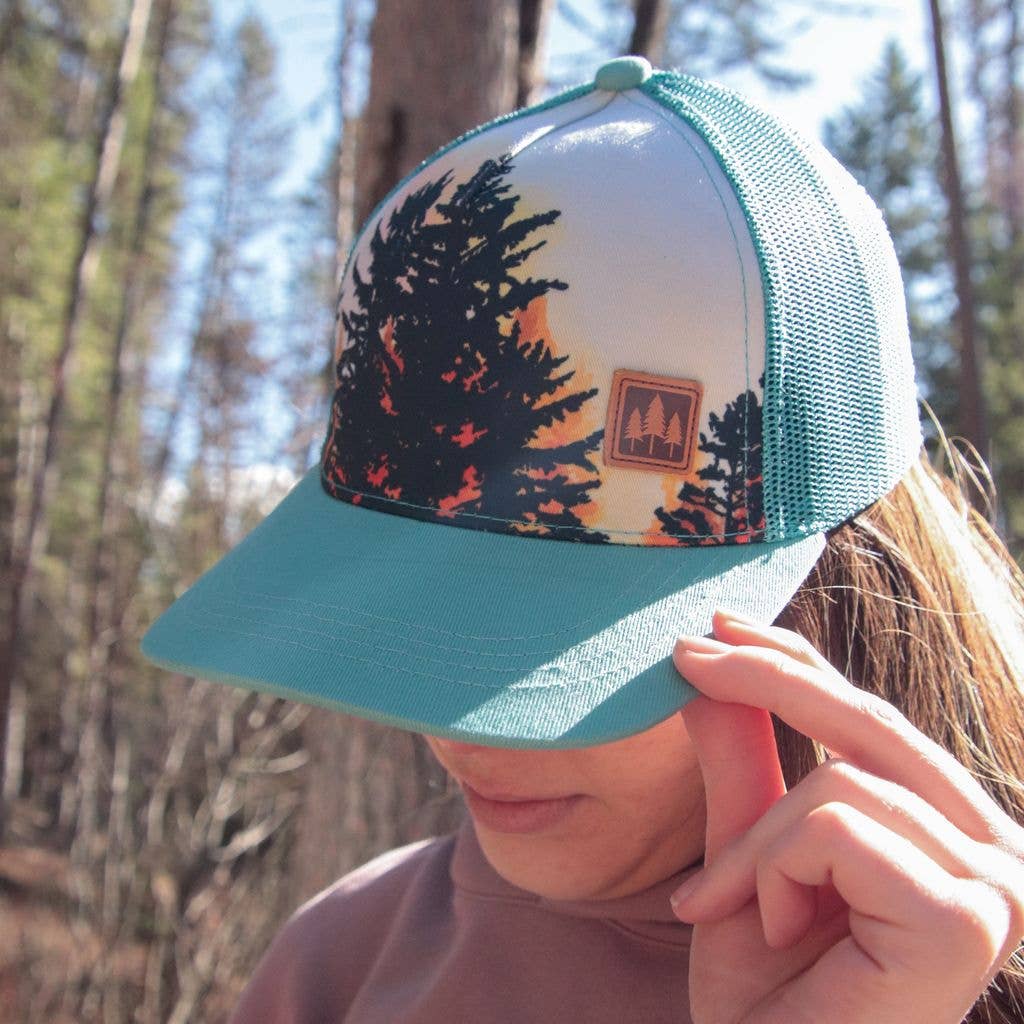 Aqua trucker hat with tree print on front and three trees on a patch