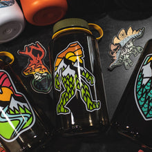 Load image into Gallery viewer, Nalgene water bottle with outdoor big foot design laying with some other stickers and water bottle

