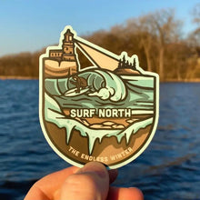 Load image into Gallery viewer, Lake Superior surfing sticker held in front of lake background
