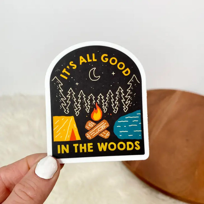 Sticker with woods, campfire, lake, and tent that says It's all good in the woods