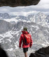 Load image into Gallery viewer, hiker in the mountains looking at view wearing red Pingora backpack
