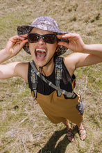 Load image into Gallery viewer, woman smiling with mouth open wearing sunglasses and bucket hat and mini Kavu rope sling bag
