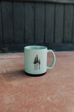 Load image into Gallery viewer, Teal mug with black tree design on a textured surface
