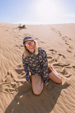 Load image into Gallery viewer, woman sitting in sand smiling wearing sunshade hoodie with wildflowers on it
