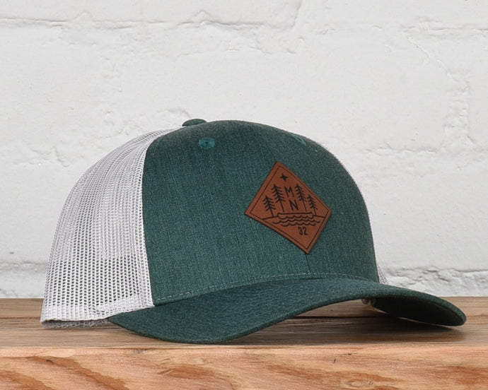 Evergreen and white snapback with leather patch that has MN, trees, and a canoe