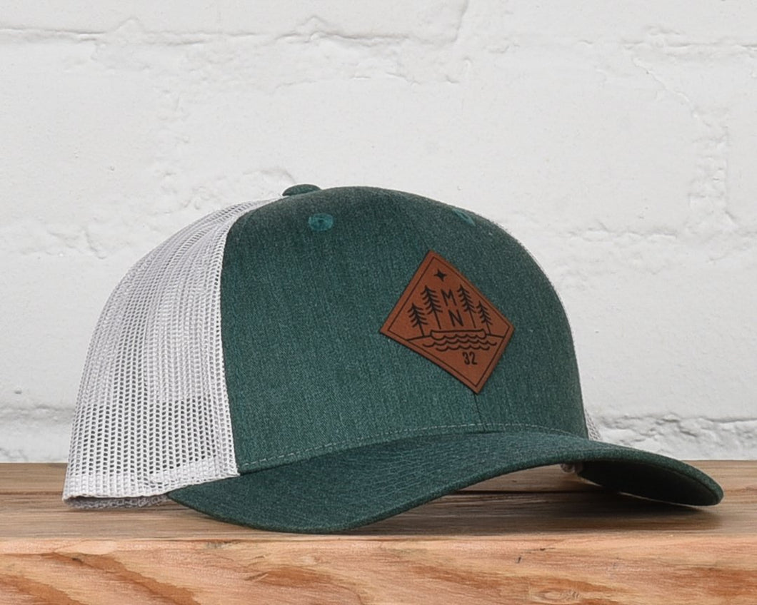 Evergreen and white snapback with leather patch that has MN, trees, and a canoe