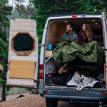 Load image into Gallery viewer, Two people in the back of a sprinter van with Rumpl blanket on their laps
