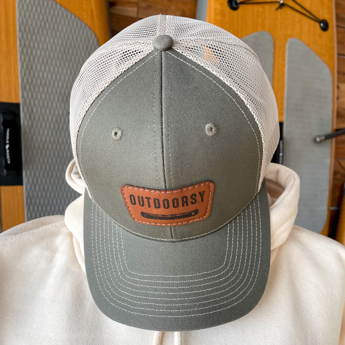 White and grey hat with patch that says outdoorsy with a canoe