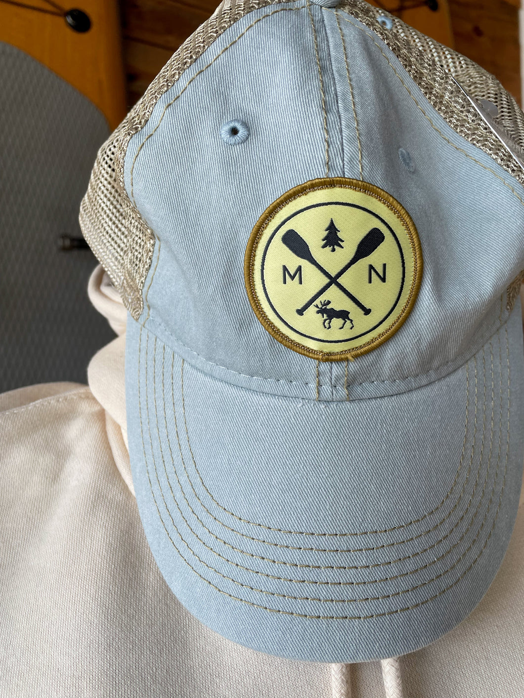 Light blue hat with patch featuring cross paddles, moose, and tree